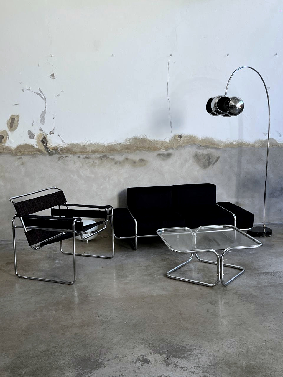 Sillón negro, mesa cromada y lámpara de arco en el espacio.